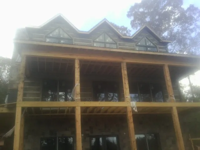 Dormers and porch framing on a large log home under construction — Roof Coating work by our crew in Fossil