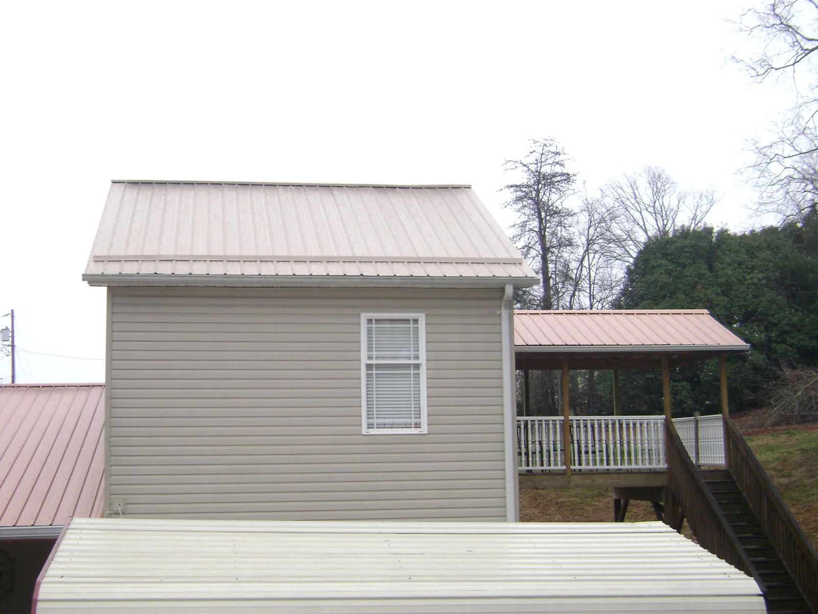 Tan metal roofs on a two story addition and attached porch, from a Roof Replacement job in Fossil